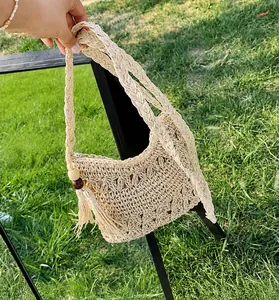 Detail van handgeweven beige strooien tas met bloemig haakwerk en kwastjes accenten