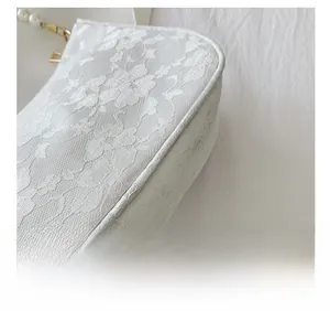 Detail of white floral lace fabric with elegant pearl handle and gold metal hardware