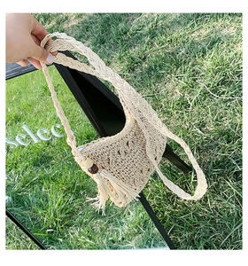 Detail of straw woven bag with fringe tassel, wooden beads, and rope shoulder strap