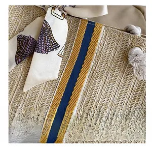 Detail view of woven straw bag featuring floral silk scarf and blue striped webbing straps