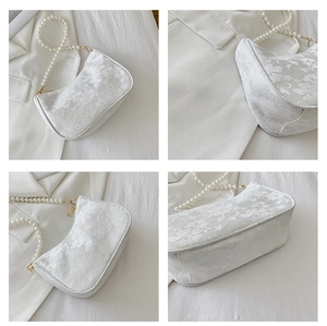 Detail of white floral lace handbag with large pearl bead shoulder strap and golden rings