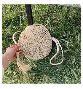 Detail of round straw bag featuring radial woven texture and stylish tassel ornament