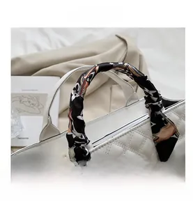 Détail de la poignée du sac matelassé blanc avec foulard décoratif en soie imprimée