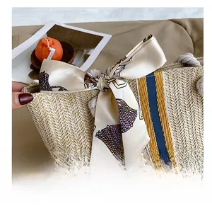 Detail of straw woven tote bag featuring striped patterns and a large silk scarf bow accent
