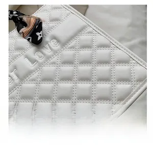 Détails macro d'un sac en cuir blanc matelassé avec broderie et foulard décoratif