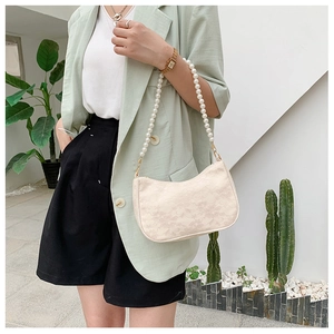 Detail of cream lace small square bag with decorative pearl strap and gold hardware