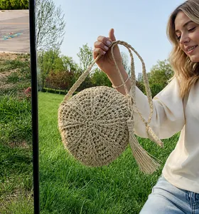 Detail van ronde rieten tas met radiale geweven textuur en zijwaartse kwastjes