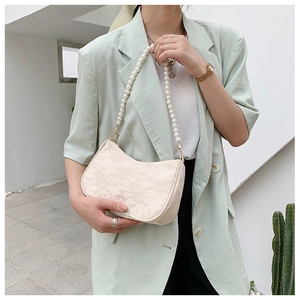 Close-up of beige lace texture and large pearl chain on this stylish shoulder bag