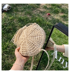 Detail of round straw shoulder bag with hollow weave and decorative tassel