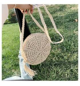 Detail view of round straw crossbody bag with radial weaving and long tassel decor