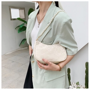Detailed view of elegant white lace shoulder bag featuring a luxury pearl chain strap