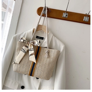 Close-up of beige woven straw tote bag featuring blue-yellow stripes and silk scarf bow