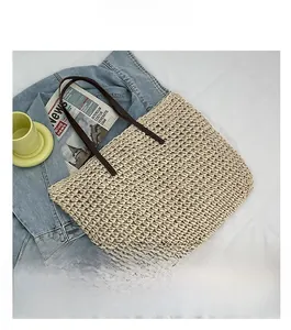 Detailed close-up of woven straw tote bag texture with slim coffee brown shoulder straps