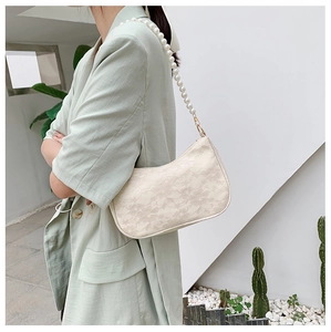 Close-up of cream lace shoulder bag with large pearl strap and crochet pattern detail