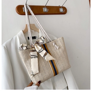 Close-up of woven straw tote bag with striped webbing and silk scarf detail