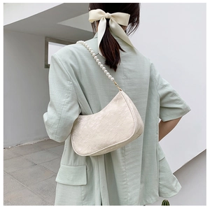 Detailed view of white floral lace hobo bag with elegant pearl shoulder strap and metal buckle