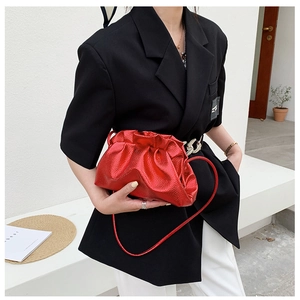 Sac nuage rouge métallique porté par un mannequin avec un blazer noir et un pantalon