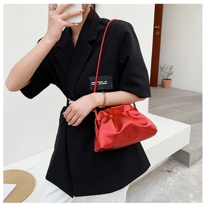 Vue détaillée du sac nuage rouge métallisé avec bandoulière fine sur un blazer noir