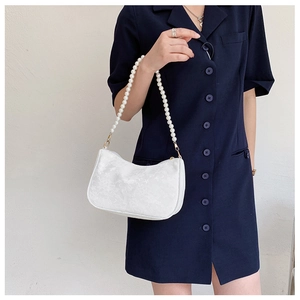 Close-up of white floral jacquard handbag with elegant pearl handle and gold hardware