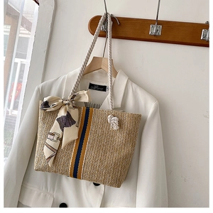 Detail of woven straw beach tote bag with printed silk scarf and cotton rope handle