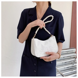 Detail of lace floral texture and large pearl handle on a white designer handbag