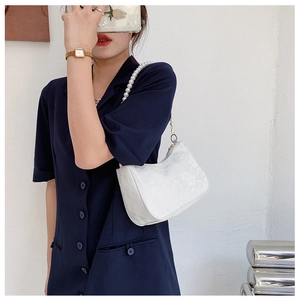 Detailed view of white floral jacquard fabric and elegant pearl strap on crescent bag