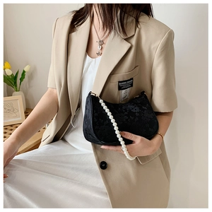 Detail of elegant black lace shoulder bag featuring large decorative white pearl strap