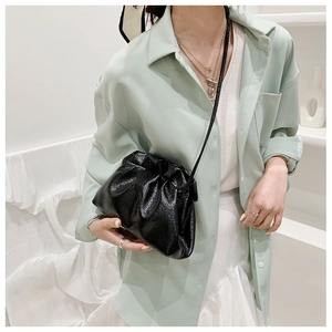 Détail du sac nuage noir avec texture cuir souple plissé porté par un mannequin