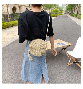 Detail of round straw shoulder bag with long tassel and woven strap in casual style