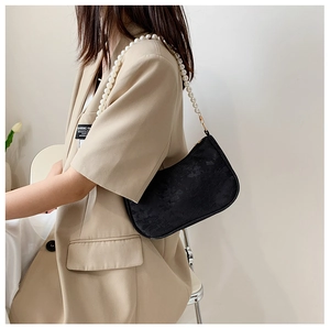Close-up of black hobo bag featuring floral embossed texture and elegant pearl strap