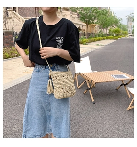 Detailed close-up of straw woven crossbody bag with long fringes and woven strap