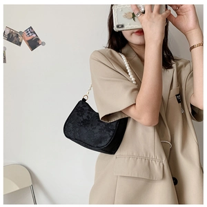 Detail of black lace embroidery underarm bag featuring elegant white pearl shoulder strap
