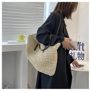 Detail of cream woven tote bag featuring high-quality dark brown leather handles