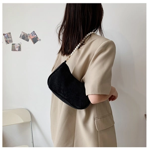 Detail of black pleated shoulder bag with white pearl strap and golden hardware