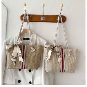 Detail of woven straw tote bag featuring rope handles and decorative silk scarf