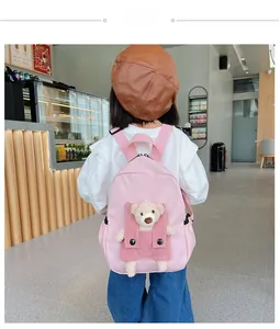 Zaino rosa per bambini con orsetto di peluche su modella in un bar