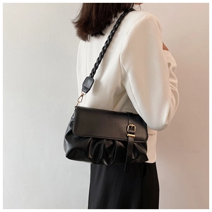 Detalle de bolso bandolera negro fruncido con correa trenzada y hebilla dorada