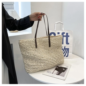 Detail of hand-woven straw tote bag with brown leather handles and textured weave