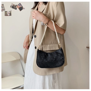 Detail view of a black jacquard moon bag with elegant white pearl chain strap