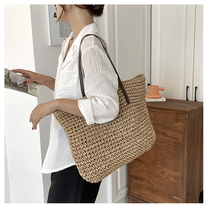 Close-up of handwoven straw tote bag with brown leather straps and intricate texture