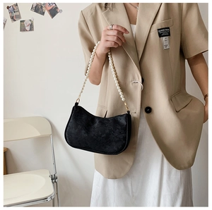 Detail of black floral jacquard bag with elegant white pearl handle on beige blazer