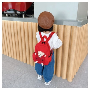 Dettaglio dello zaino rosso per bambini con simpatico orsetto 3D su sfondo minimal