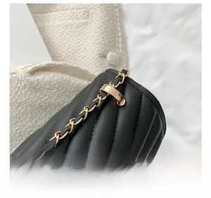 Detail shot of the gold metal connector and chain strap on black quilted leather bag