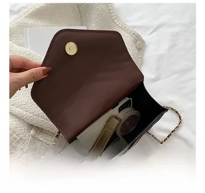 Interior view of small brown leather crossbody bag with chain strap showing daily essentials