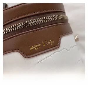 Detailaufnahme der braun-weißen Kontrasttasche mit Krokostruktur und Goldreißverschluss