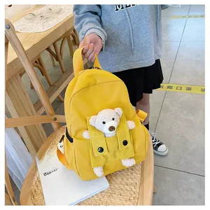 Dettaglio dello zaino giallo per bambini con tasca in velluto e simpatico orsetto