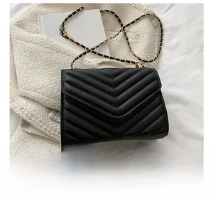 Detailed view of black V-quilted faux leather bag next to phone for size reference