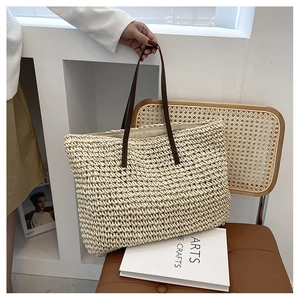 Detail of hand-woven cream tote bag with dark brown leather handles on wooden chair