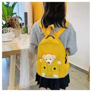 Dettaglio dello zaino giallo per bambini con un grazioso peluche di orsetto inserito