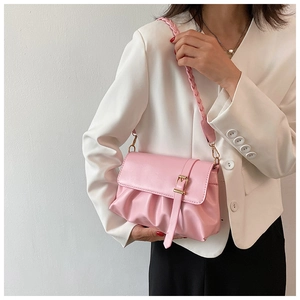 Close-up of pink pleated shoulder bag with decorative belt buckle and woven strap